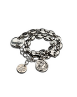 Silver chain bracelet with three charms on a white background