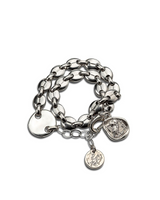 Silver chain bracelet with various charms on a white background