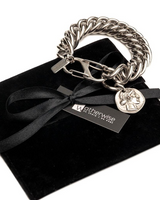Silver chain bracelet with a tag on a black velvet cushion, branded 'Otherwise'.