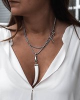 Close-up of a woman wearing a white blouse and layered silver necklaces.