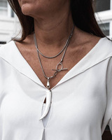 Close-up of a woman wearing a silver necklace with a building in the background