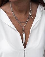 Close-up of a person wearing a white shirt with layered silver necklaces.
