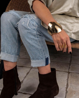 Honey Gold Geometric Cuff bracelet worn on a model’s wrist, featuring a smooth, chunky design paired with casual ripped jeans.