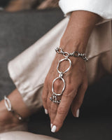 Stainless Steel Hand Harness features a bold silver chain connecting a ring to a wrist bracelet, worn comfortably on a hand.