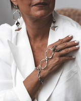 Handcrafted stainless steel hand harness featuring a connected ring and wrist bracelet, worn over a white blazer.