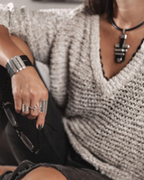 Statement black leather and metal bar choker necklace with sleek metal accents, worn with a casual sweater and jeans.
