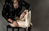 Funky silver-plated metal ring worn on the finger, featuring a hammered finish and adjustable fit, paired with leather pants.