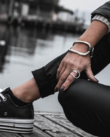 Person wearing black sneakers and black pants with a blurred waterfront background