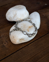 Stainless steel anklet featuring oval links, displayed on white stones, with a sleek, minimalist design.