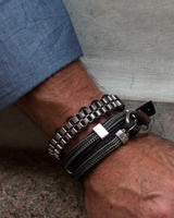 Close-up of a wrist wearing multiple bracelets on a textured surface