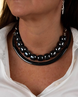 Layered gunmetal and black choker set featuring smooth semi-precious gemstones and sleek metal tubes worn together.