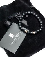Black beaded bracelet on a black velvet pillow with 'otherWise Jewelry' tag.