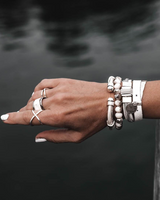 Zamak metal leather cuff bracelet with white and silver stacked bangles, worn on a woman's wrist with a spring opening.