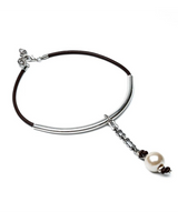 A silver-toned metal bracelet featuring a polished cylindrical bar, a delicate chain link, and a dangling charm with a white pearl bead and small dark brown beads, all set against a plain white background.
