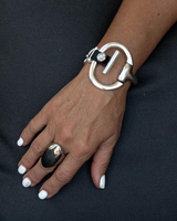 Black leather cuff bracelet featuring a sculpted horsebit centerpiece, worn on a hand with a bold silver ring.