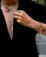Person wearing a silver necklace and bracelet with a blurred background