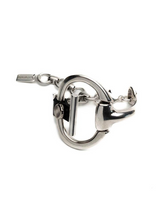 Black leather and metal cuff bracelet featuring a central horsebit design, showcasing a bold, brutalist style.