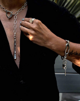 Person wearing a silver necklace and bracelet with a blurred background