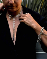 Person wearing a black outfit with silver necklaces and bracelets.