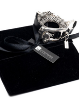 A silver-toned metal bracelet with a woven black-and-white patterned section, displayed on a black velvet pouch tied with a black ribbon and tag. The tag reads 'otherwise'.