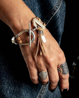 Hand wearing multiple bracelets and rings with a dark background