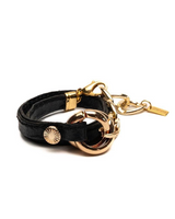 Black leather bracelet with gold accents on a white background