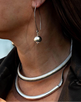 Close-up of a person wearing silver hoop earrings and necklaces.