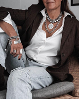 Layered gemstone and stainless steel chain necklace set worn with an open white shirt and brown blazer, showcasing a bold, layered look.