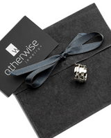 Adjustable silver-plated ring with a unique geometric design, presented on a dark suede pouch with a ribbon.