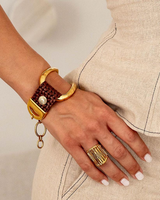 Gold bracelet and ring on a hand with a neutral background