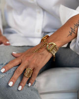 Close-up of a hand wearing gold bracelets and rings with a blurred background