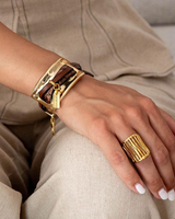 Gold bracelet and ring on a hand with beige pants