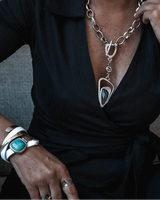 Person wearing a black top with a silver necklace and turquoise jewelry.