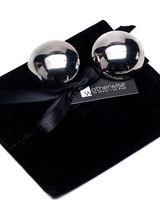 Oversized dome stud earrings with a polished metallic finish resting on a black suede pouch, featuring a ribbon.