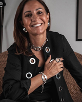 Oversized metallic dome stud earrings worn by a woman with long hair, styled with a black blazer and layered jewelry.