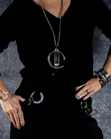 Person wearing a black outfit with jewelry on a gray textured background