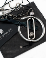 Silver necklace with a pendant on a black jewelry pouch, branded 'otherwise jewelry'.