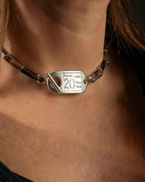 Close-up of a person wearing a silver bracelet with a tag on their wrist.