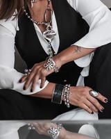 Person wearing multiple silver jewelry pieces including a necklace, bracelet, and ring.