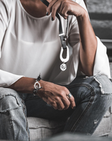 Person wearing a white shirt and ripped jeans, holding a keychain with a pendant.