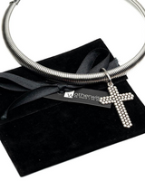Silver necklace with a cross pendant on a black velvet surface with 'Motherwis' branding.