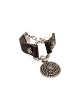 Brown leather cuff bracelet featuring a horsebit buckle and a white opal Swarovski crystal pendant, adorned with a metal chain.