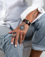 Brown leather cuff bracelet featuring a horse bit buckle and white opal Swarovski crystal pendant, worn on a model's wrist.