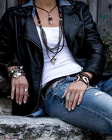 Person wearing a black leather jacket, white top, and blue jeans sitting on a stone ledge.