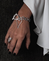 Chunky heart statement set with a silver bracelet featuring a heart pendant, worn on a model's wrist.