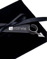 Black suede gift pouch with a satin ribbon, featuring a chunky heart ring with a silver heart pendant attached.