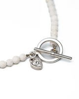 Lava stone choker with a silver T-clasp and a small crystal charm, featuring a textured white bead design.