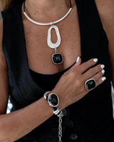 Chunky black resin necklace featuring a silver-plated Zamak metal tube and leather strands, worn with matching ring and bracelet.