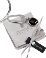 Chunky black resin necklace featuring a silver-plated tube and a standout black pendant, presented on a gray suede pouch.