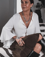 Chunky silver love necklace with large heart pendant worn with a white blouse and layered jewelry, showcasing an edgy style.